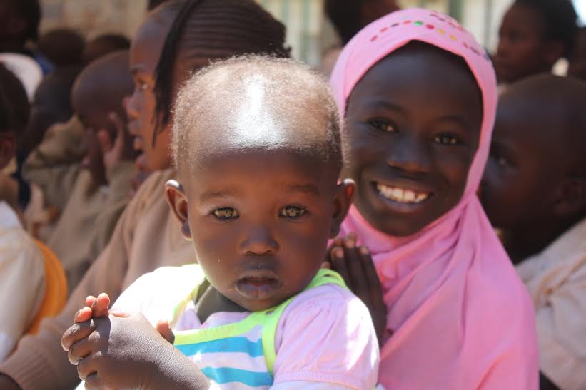 An Image of two smiling children in Sudan in a sea of other children.