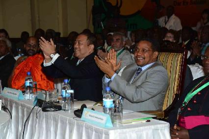 An image of two men sitting at a table, clapping proudly at the GRNC Fourth Forum Conference.
